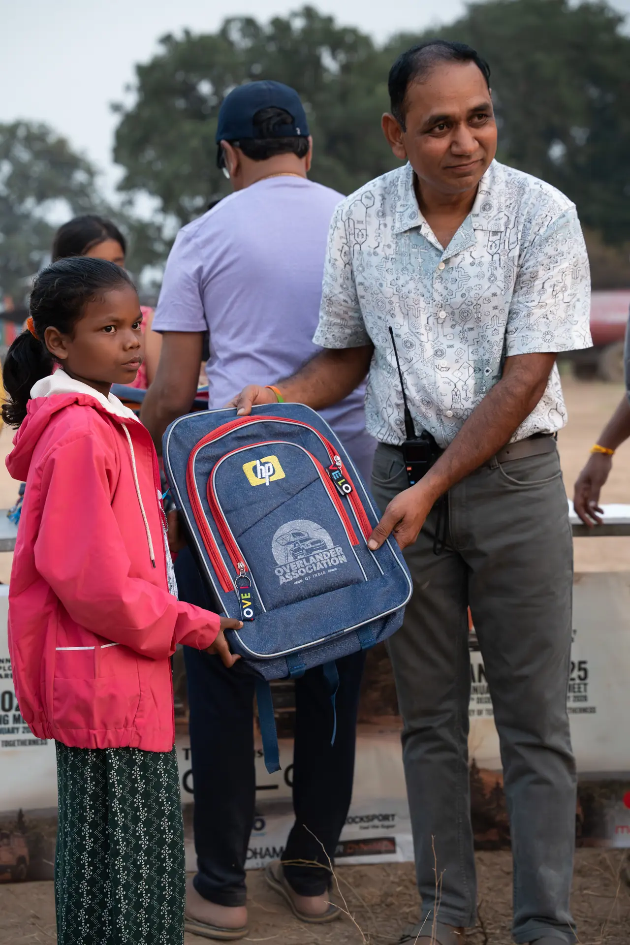 An OAI member handing over a branded school backpack to a child