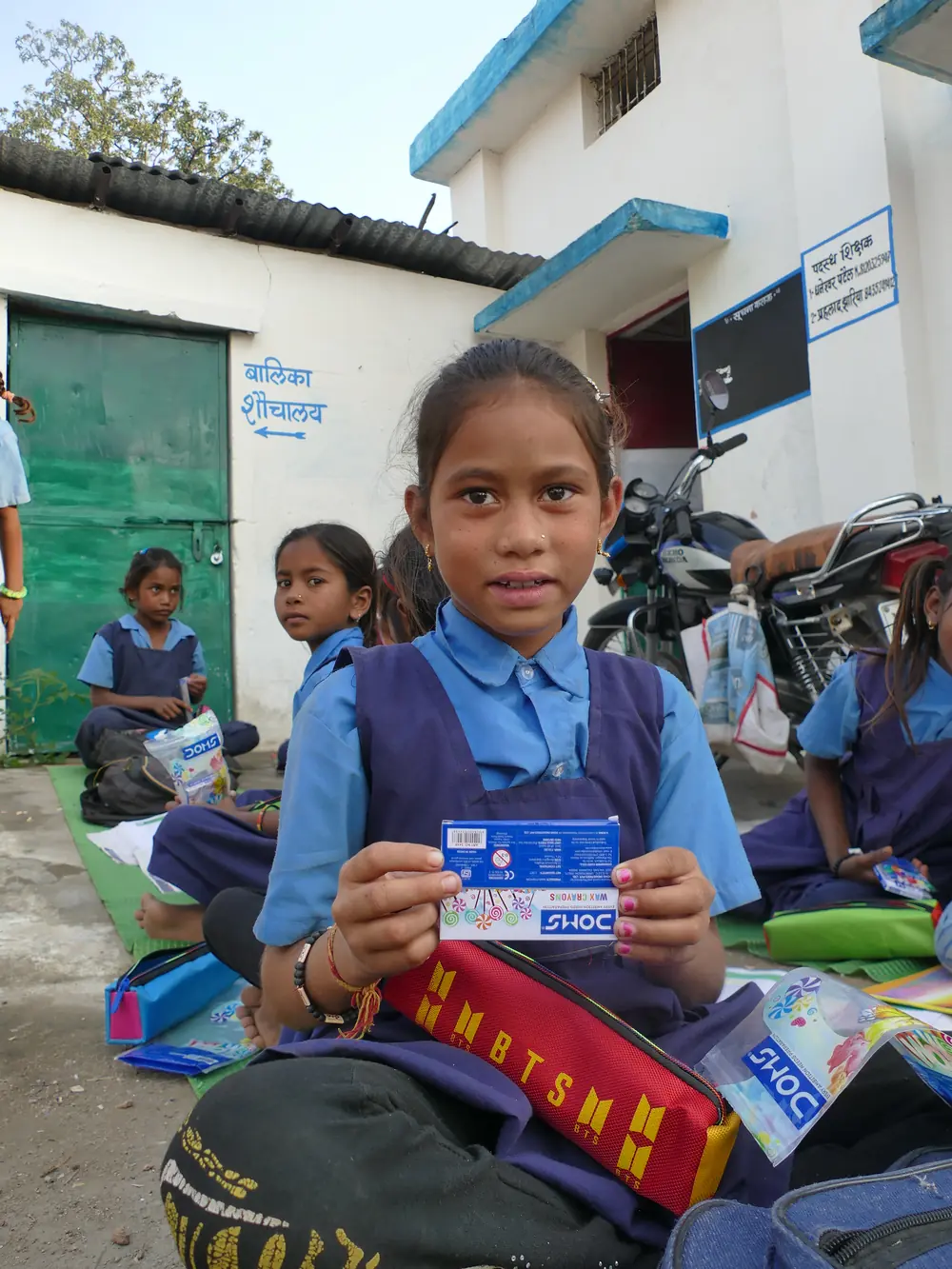 A schoolgirl holding a new box of crayons from her stationery kit