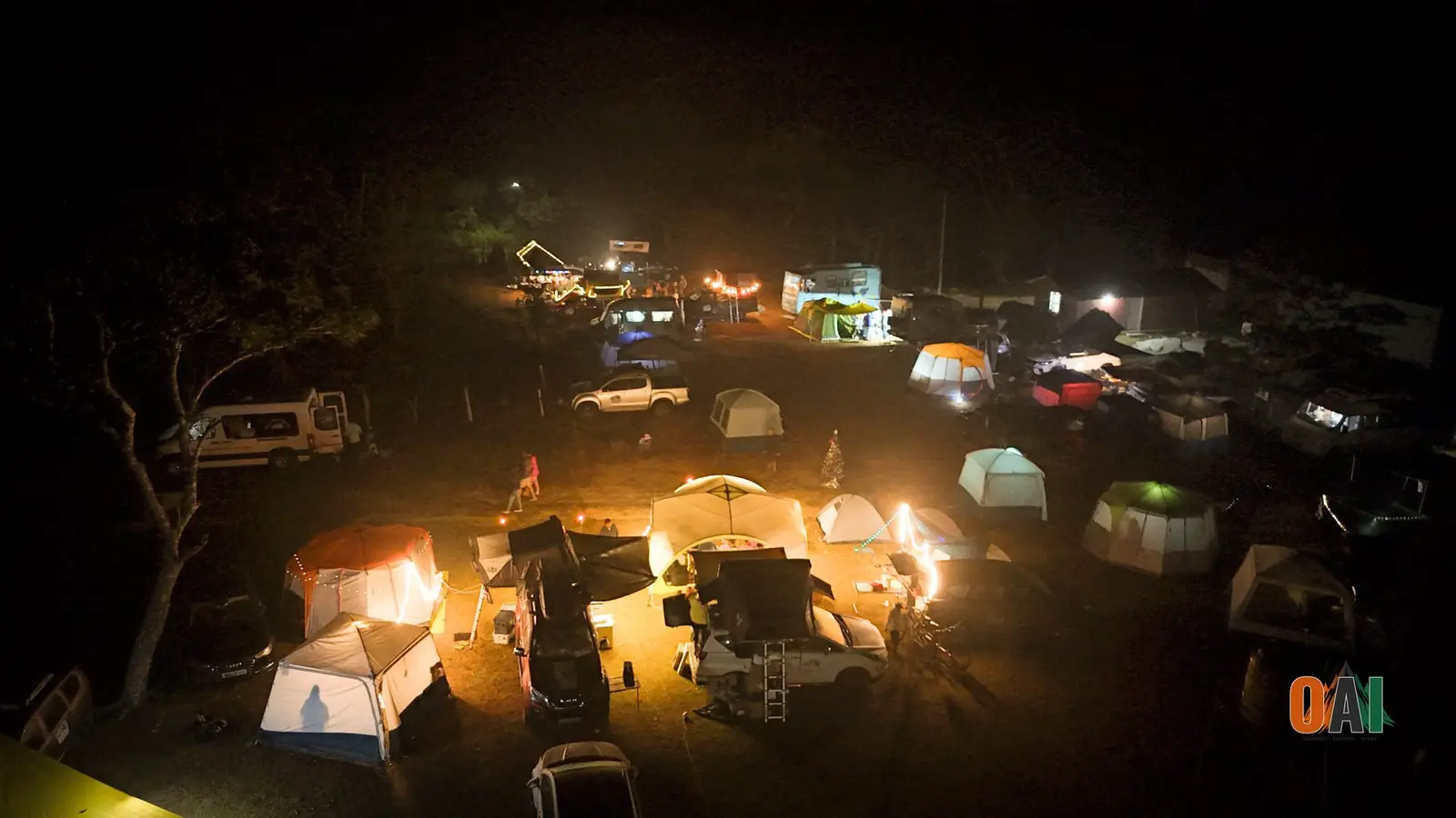 Aerial night view of an illuminated OAI campsite with tents and campervans