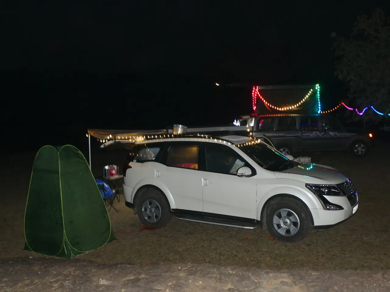 SUVs strung with festive lights at a members' night camp