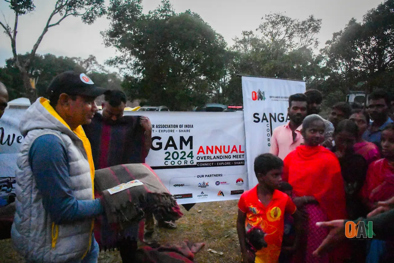 Blanket distribution in front of the Sangam 2024 Coorg banner