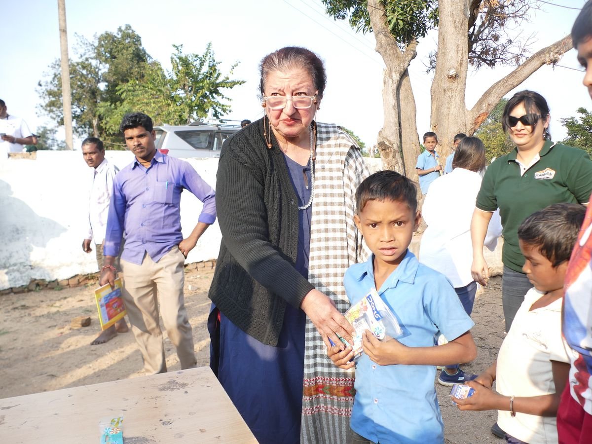 An OAI member handing school stationery to a child at a rural distribution drive